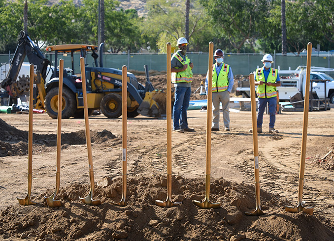Photo of groundbreaking ceremony shovels standing upright in dirt at the construction site