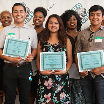 A group of students hold up scholarship certificates