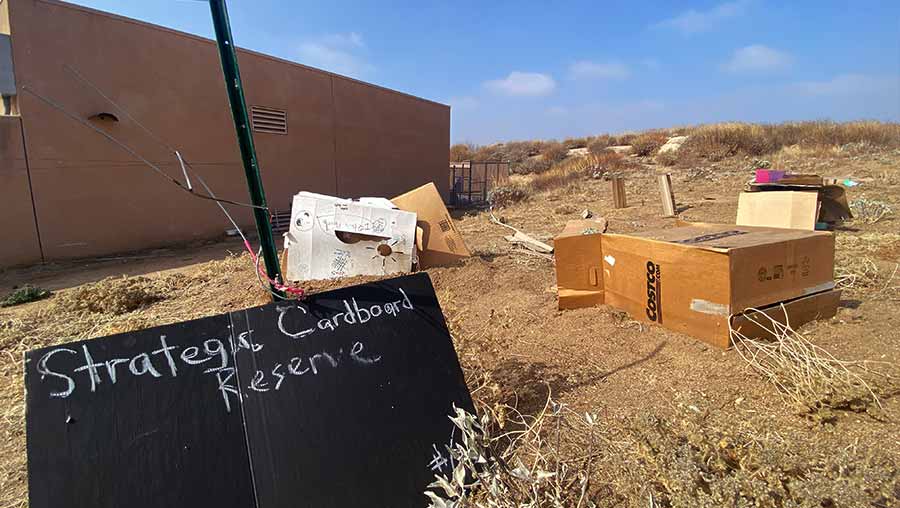 Making Refuge installation showing a gathering of cardboard boxes next to exhibition label