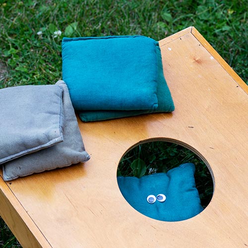 Close up of a cornhole board and blue and gray bean bags