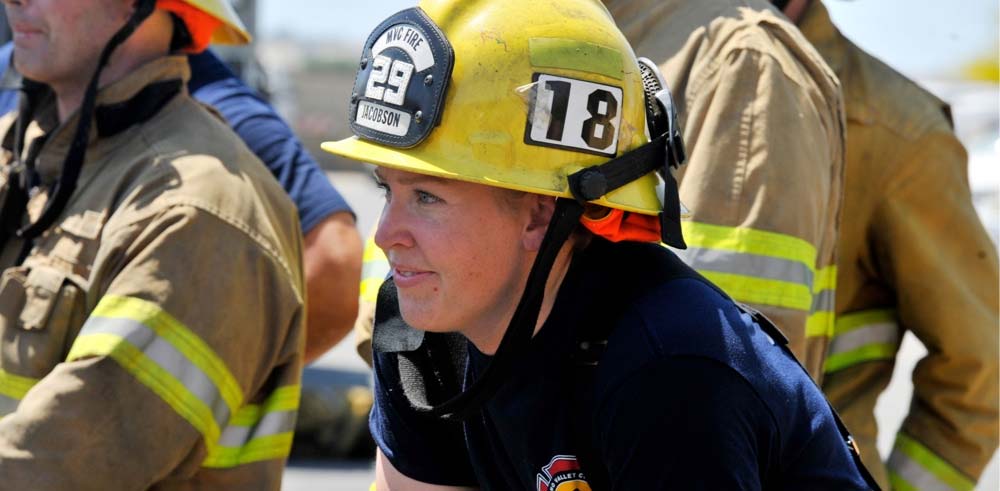 A firefighter cadet wearing a helmet rests during training