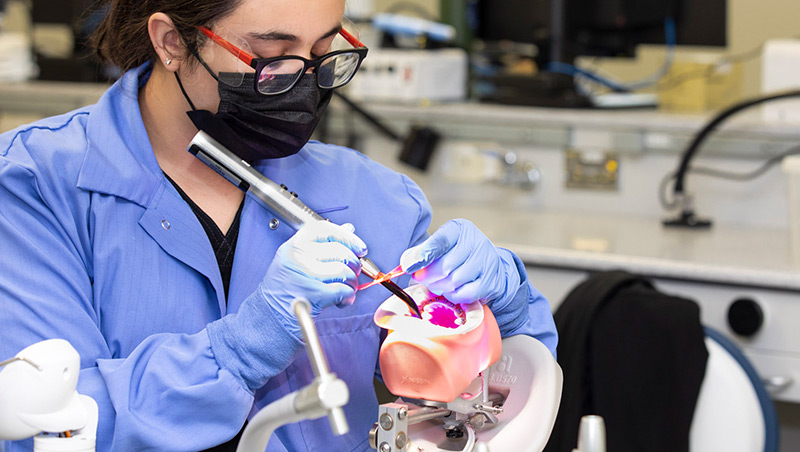 A dental assisting student practices cleaning the teeth