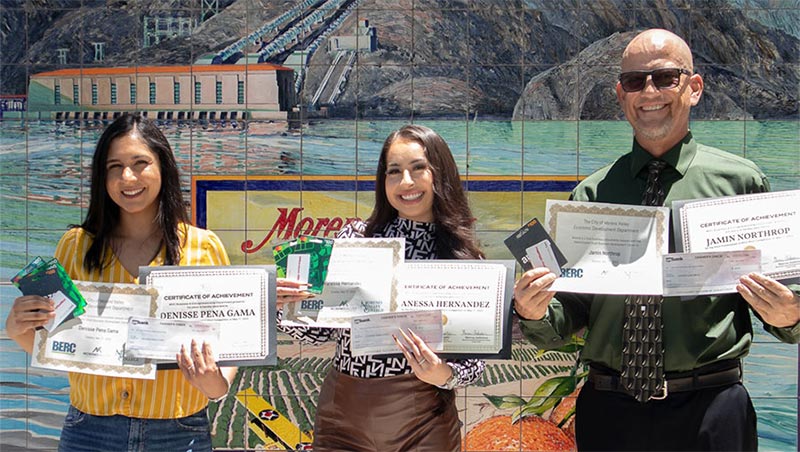 Three students stand with pitch contest certificates awards