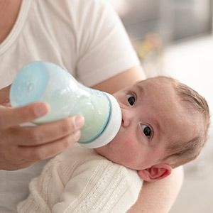 A nursing infant drinks from a baby bottle