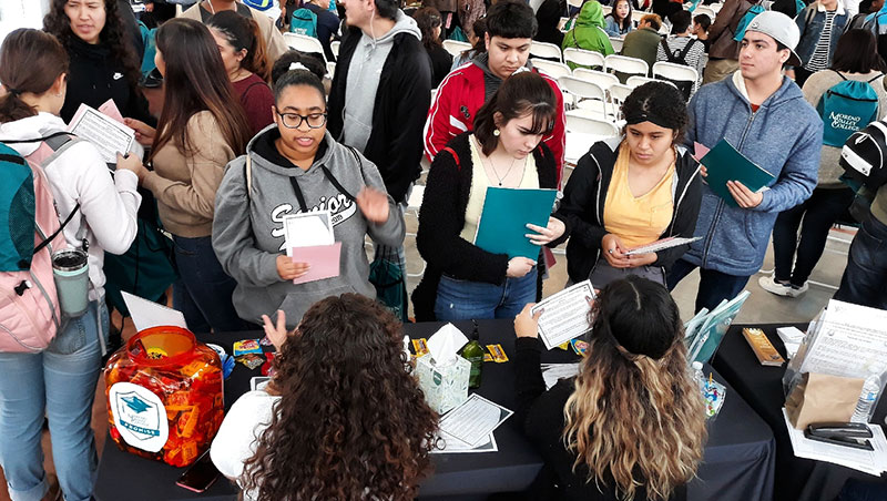 Students gather around a table featuring Promise Initiative information