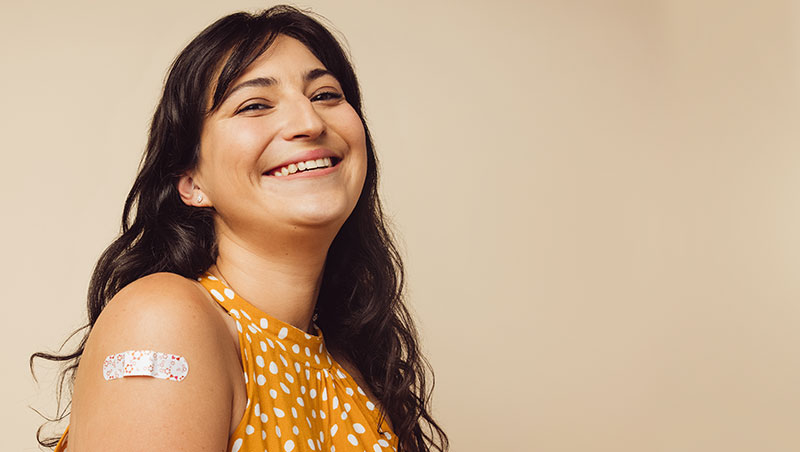A woman received a vaccine and shows off a bandaid on her arm