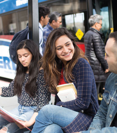 Three students sit at an RTA bus stop socializing